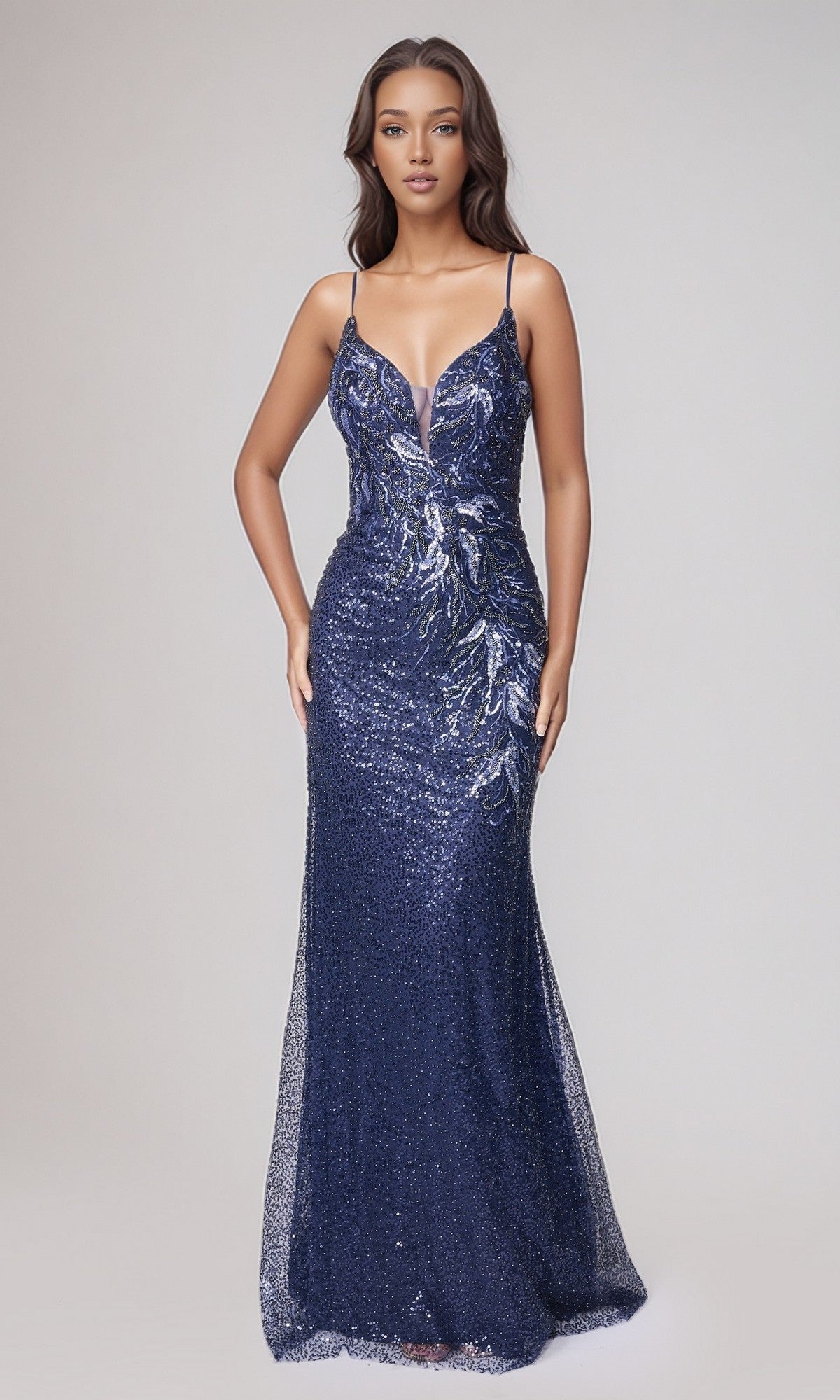 A woman wears the Long Formal Dress: Nina Canacci 7656 in navy—a floor-length, form-fitting sequin gown with thin straps and a deep V neckline—against a plain light background.