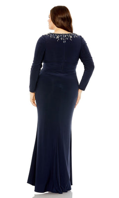 A woman wearing the Long Plus-Size Prom Dress 77023 by Mac Duggal, featuring long sleeves, a navy blue hue, and an embellished neckline, stands with her back to the camera.