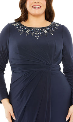 A woman wears the Mac Duggal Long Plus-Size Prom Dress 77023, a navy blue formal gown with long sleeves, a gathered waist, and an embellished neckline adorned with beads and sequins.
