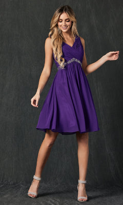 A woman wearing the Juliet 786 short semi-formal dress—sleeveless, knee-length, purple a-line with a jeweled waistband—stands against a dark textured background.