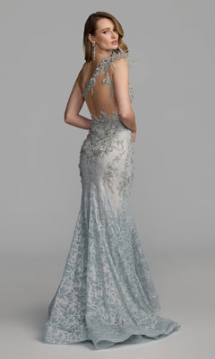 A woman stands and poses against a plain gray background wearing the Feather One-Shoulder Prom Gown: Mac Duggal 79264—a light blue, backless mermaid dress adorned with delicate lace, floral embroidery, and shimmering beaded detailing.
