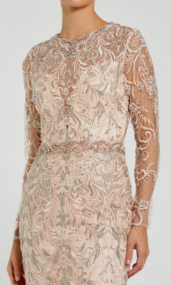 Woman wearing the Beaded Long Pink Formal Dress: Mac Duggal 79267—a long-sleeve gown featuring nude tones, sheer detailing, and intricate silver and pink embroidery with beadwork on the bodice and sleeves.