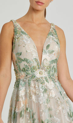 A woman wears the Mac Duggal 79329, a long cream floral prom dress featuring a sleeveless cut, deep V-neckline, pastel embroidery, and delicate bead embellishments—a stunning choice for any special event.