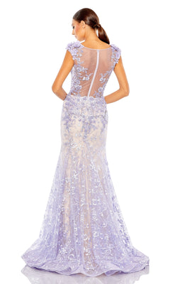 A woman with a low ponytail models the Long Formal Dress 79357 by Mac Duggal, a floor-length fitted lilac mermaid dress with floral appliqué and an open back, seen from behind.