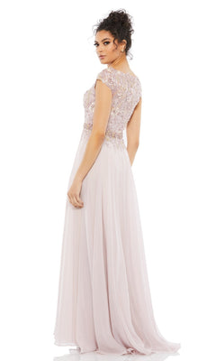 A woman in the Cap-Sleeve Long Formal Dress: Mac Duggal 79365, a floor-length light pink gown with an embellished bodice, stands facing backward and looks over her shoulder.