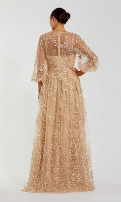 A woman stands facing away, her hair in a neat bun, wearing the Mac Duggal 79399 long sleeve blue formal dress with sheer nude fabric and floral embroidery.