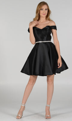 A woman wearing the Off-Shoulder Short Mikado Homecoming Dress 7948 with a flared skirt, silver belt, and silver high heels stands against a plain light background.