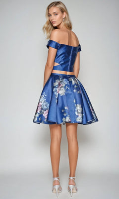 Woman in the Short Party Dress: Juliet 798 stands with her back to the camera, wearing a blue off-the-shoulder top and matching floral A-line skirt paired with white high-heeled sandals.