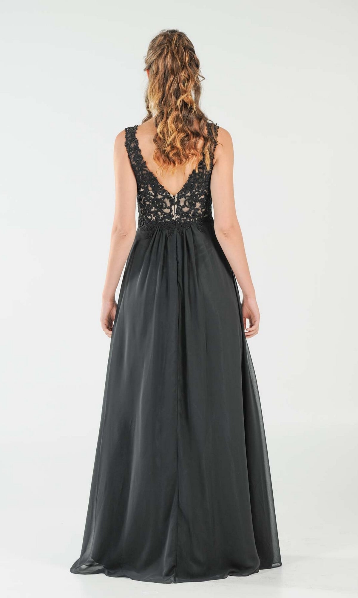 A woman with wavy hair faces away, wearing the Sleeveless V-Neck Chiffon Long Prom Dress 8012, featuring an elegant open back, lace bodice, and a flowing skirt.