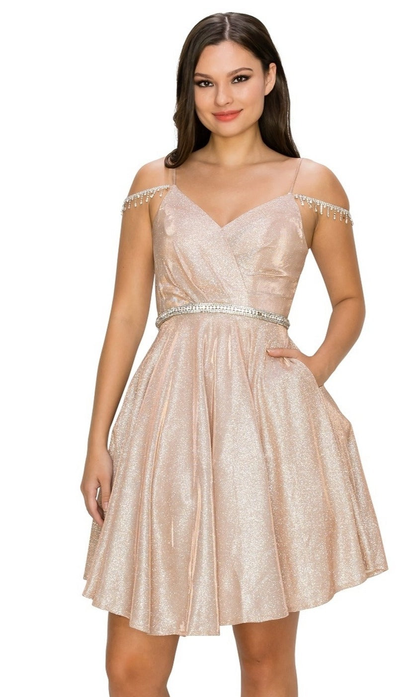 Woman models the Beaded Cold-Shoulder Short Homecoming Dress 8014J, a shimmery light pink semi-formal dress with thin straps, off-the-shoulder design, fitted waist, and playful short skirt—standing with one hand in her pocket.