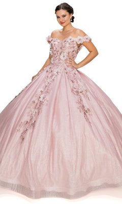A woman wears the Quinceanera Ball Gown 8020J, featuring a sparkling off-the-shoulder design with 3D floral accents and a glittery skirt, standing against a plain white background.