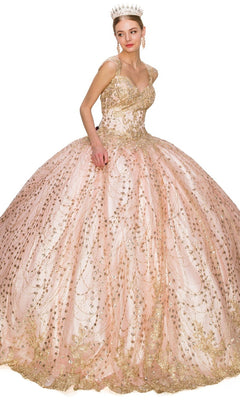 A woman in the Quinceanera Ball Gown 8024J, featuring pink glitter tulle and gold embellishments with a tiara, stands against a white background.