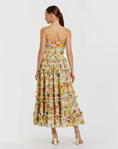 A woman faces away in the Mac Duggal 8026 Midi Print Wedding Guest Dress, featuring a sleeveless floral design with ruffle details and strappy heels—a stylish pick for wedding guests.