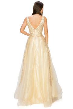 A woman stands facing away, wearing the A-Line Gold-Embroidered Long Prom Ball Gown 8029J—a floor-length, sleeveless gold dress with a deep V-back and delicate lace detailing.