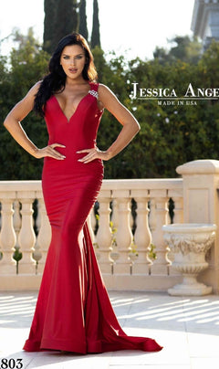 Woman in a fitted, sleeveless red Backless Long V-Neck Prom Dress: Jessica Angel 803, standing outdoors by a stone balustrade. Made in USA.