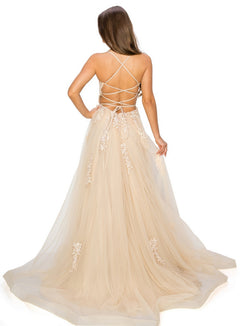 A woman faces away wearing the Floral-Embroidered Long Tulle Prom Dress 8031J, a floor-length champagne gown featuring lace details, a low back, crisscrossing straps, and delicate floral embroidery.