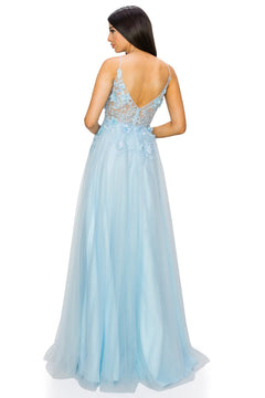 A woman stands with her back to the camera, wearing the Sheer-Bodice Long A-Line Prom Ball Gown 8038J in light blue, featuring a floor-length skirt, sheer embroidered back, and delicate 3-D floral designs.