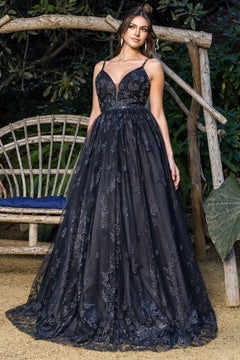 A woman poses outdoors by a rustic wooden bench in the Corset-Back Long Glitter Prom Ball Gown 8039J, a floral embellished dress with a deep neckline, floor-length skirt, and delicate embroidery, surrounded by lush greenery.
