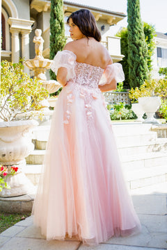 A woman in the Puff-Sleeve Long Sweetheart Prom Ball Gown 8042J stands outdoors by a staircase and garden. The gown features pink fabric, off-the-shoulder puff sleeves, a long silhouette, and beaded floral details.