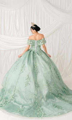 A woman in the Quinceanera Ball Gown 8045J, featuring off-the-shoulder design, 3D floral details, and glitter lace embroidery, stands with her back to the camera wearing a tiara before draped white fabric.