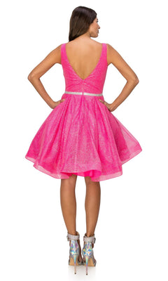 A woman faces away wearing the Short Glitter Princess Homecoming Dress 8047J—a sleeveless, knee-length, bright pink party dress with a flared skirt and deep V-back—paired with metallic high heels.