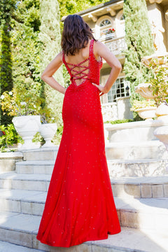 A woman in the Strappy-Back Embellished Long Prom Dress 8048J, featuring beaded shoulder straps and a lace-up back, stands on outdoor stone steps facing away from the camera.