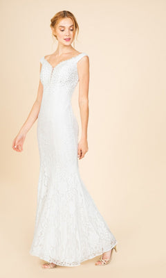 A woman in the Eureka 8050 long prom dress—an off-white, floor-length lace gown with a fitted bodice and subtle bead accents—poses against a plain beige background.