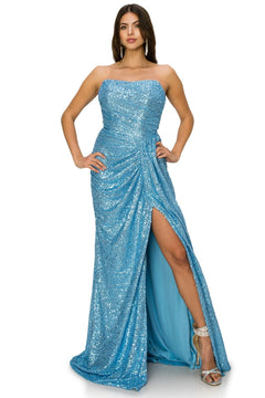 A woman stands confidently with one leg forward and hands on hips, wearing the Allover-Sequin Long Strapless Prom Dress 8052J—floor-length, blue, with a thigh-high slit—paired with high-heeled sandals.