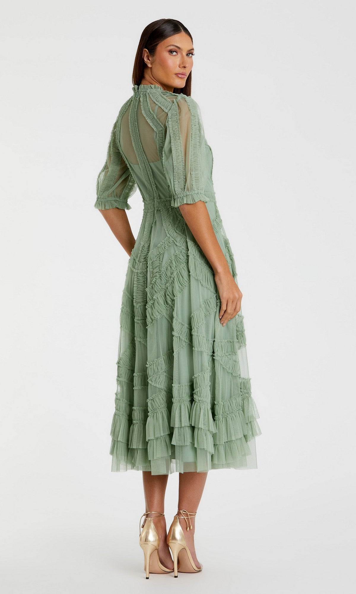 A woman stands against a plain background, wearing the Mac Duggal 8058 Ruffled Midi Wedding-Guest Dress in light green with textured fabric and ruffled sleeves, paired with metallic high heels.