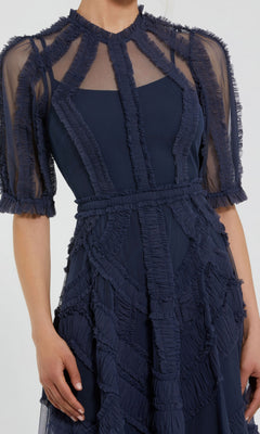 A woman wearing the Mac Duggal 8058 Ruffled Midi Wedding-Guest Dress in navy blue, featuring sheer short sleeves and decorative ruffled geometric trim on the bodice and skirt.
