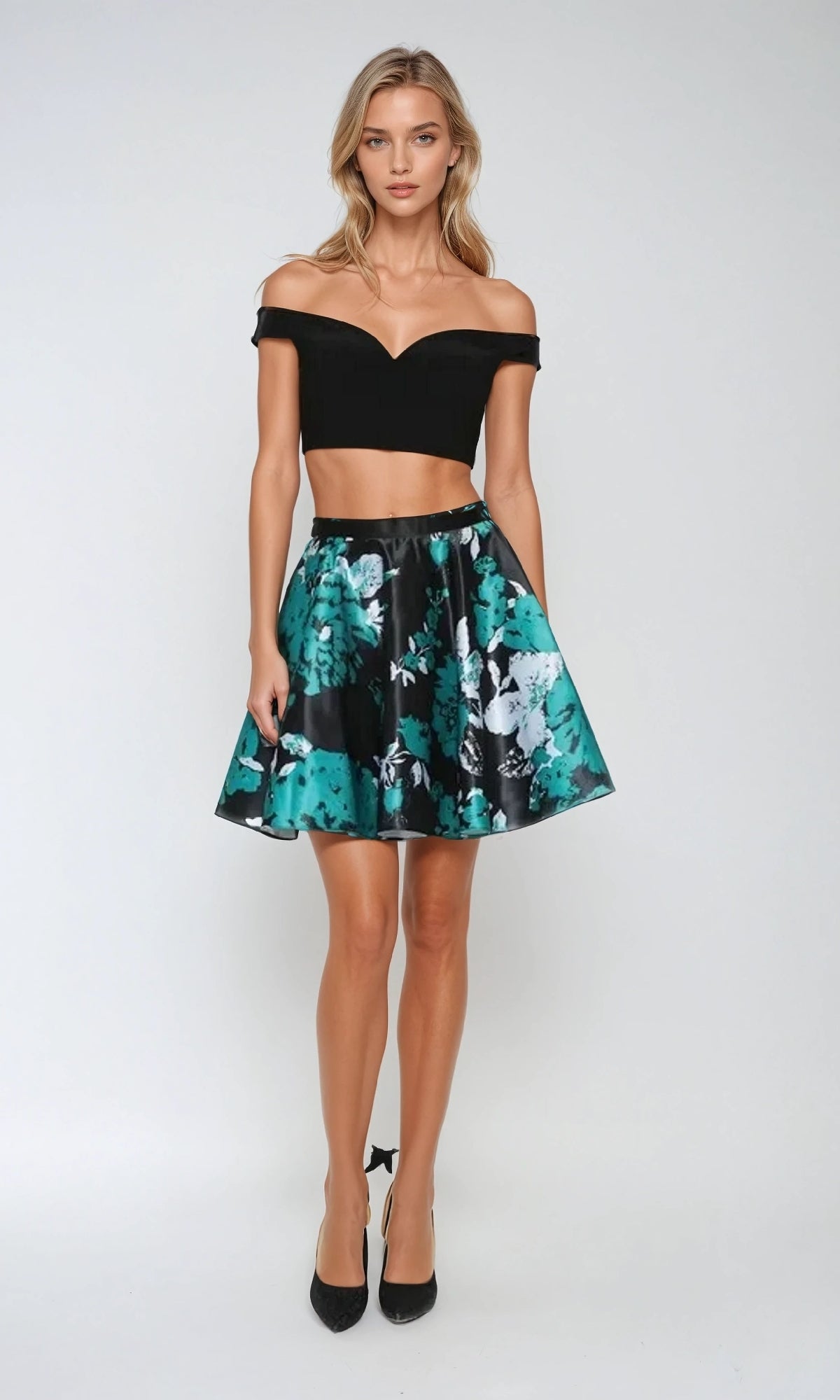 A woman poses against a plain background wearing the Juliet 805 short two-piece Hoco dress, featuring a black off-the-shoulder crop top and a green floral A-line skirt.