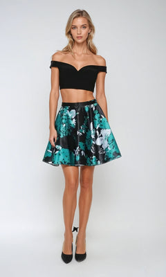 A woman poses against a plain background wearing the Juliet 805 short two-piece Hoco dress, featuring a black off-the-shoulder crop top and a green floral A-line skirt.