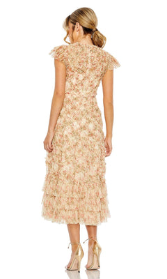 A woman stands with her back to the camera in the Mac Duggal 8060 Cap-Sleeve Wedding Guest Dress, featuring a floral print, ruffled layers, and cap sleeves, styled with gold high-heeled sandals.