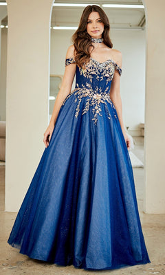 A woman stands indoors wearing the Amelia Couture 8063 long prom dress—royal blue, off-the-shoulder, with gold floral embroidery and sequin appliqué—paired with a matching choker.