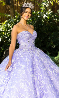 A woman wearing a jeweled crown and the Cinderella Couture 8071J quinceanera dress with intricate silver embroidery stands outdoors, smiling.
