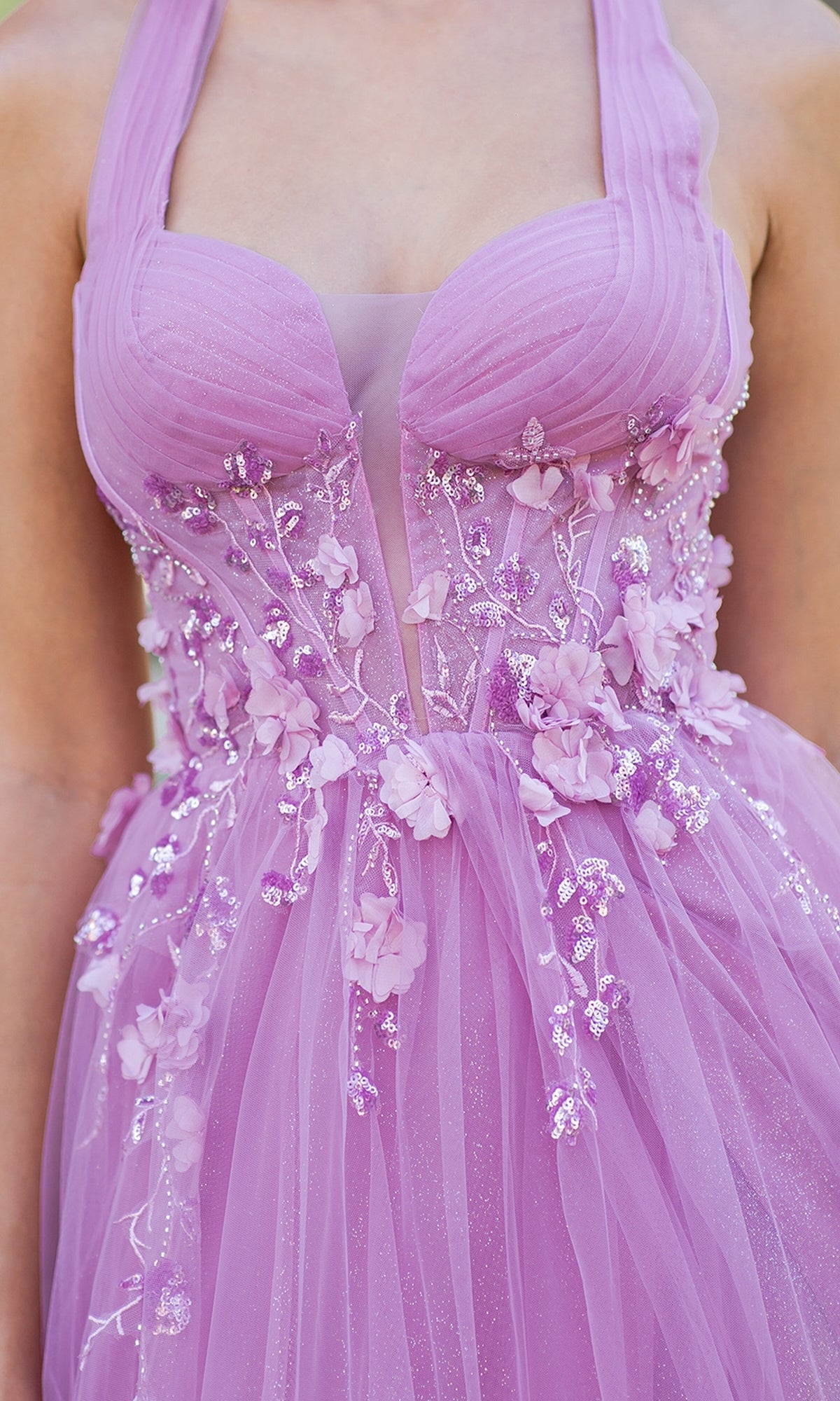A close-up of a person wearing the Cinderella Couture 8076J, a long halter prom dress in lavender with sheer panels, floral appliqués, and glitter details on the bodice and skirt.