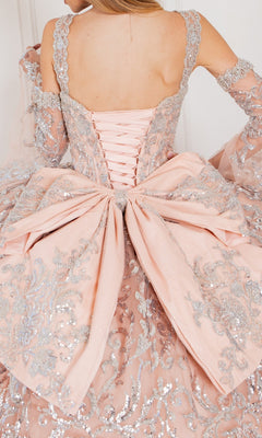 A close-up of a person wearing the Quinceanera Ball Gown 8080J, featuring a pink ombre design, silver embroidery, lace-up back, and a large decorative bow at the waist.