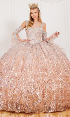 A woman poses indoors wearing the Quinceanera Ball Gown 8080J, a stunning ombre dress with silver embellishments and a crown.