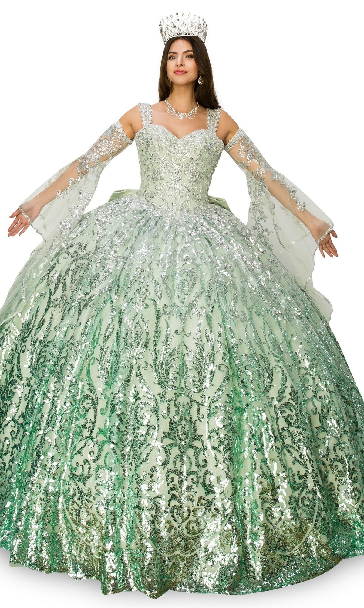 A woman wearing the Quinceanera Ball Gown 8080J, a jeweled crown, necklace, and long gloves stands with arms outstretched against a white background.
