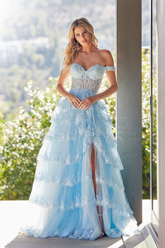 Amelia Couture 8085 is a baby blue off-the-shoulder ball gown with a corset-style bodice, a tiered skirt, a high leg slit, and silver lace appliques throughout.
