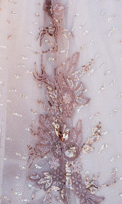 Close-up of sheer fabric with intricate floral embroidery and scattered sequins in soft, metallic tones—an elegant detail featured in the Quinceanera Ball Gown 8087J, ideal for a shimmering ball gown or off-the-shoulder look.