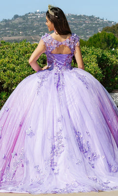 A person in the Quinceanera Ball Gown 8088J, featuring lavender 3D floral lace appliqué and a tiara, stands outdoors with their back to the camera, facing lush greenery and distant hills.