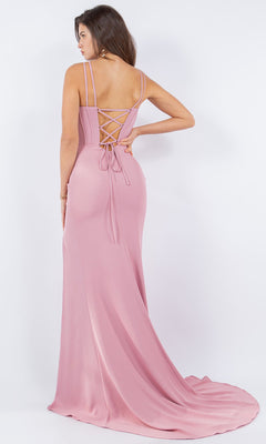 A woman wearing the Strappy Corset Prom Dress: Cinderella Couture 8091J—a floor-length, light pink satin gown with a lace-up back and spaghetti straps—stands facing away from the camera.