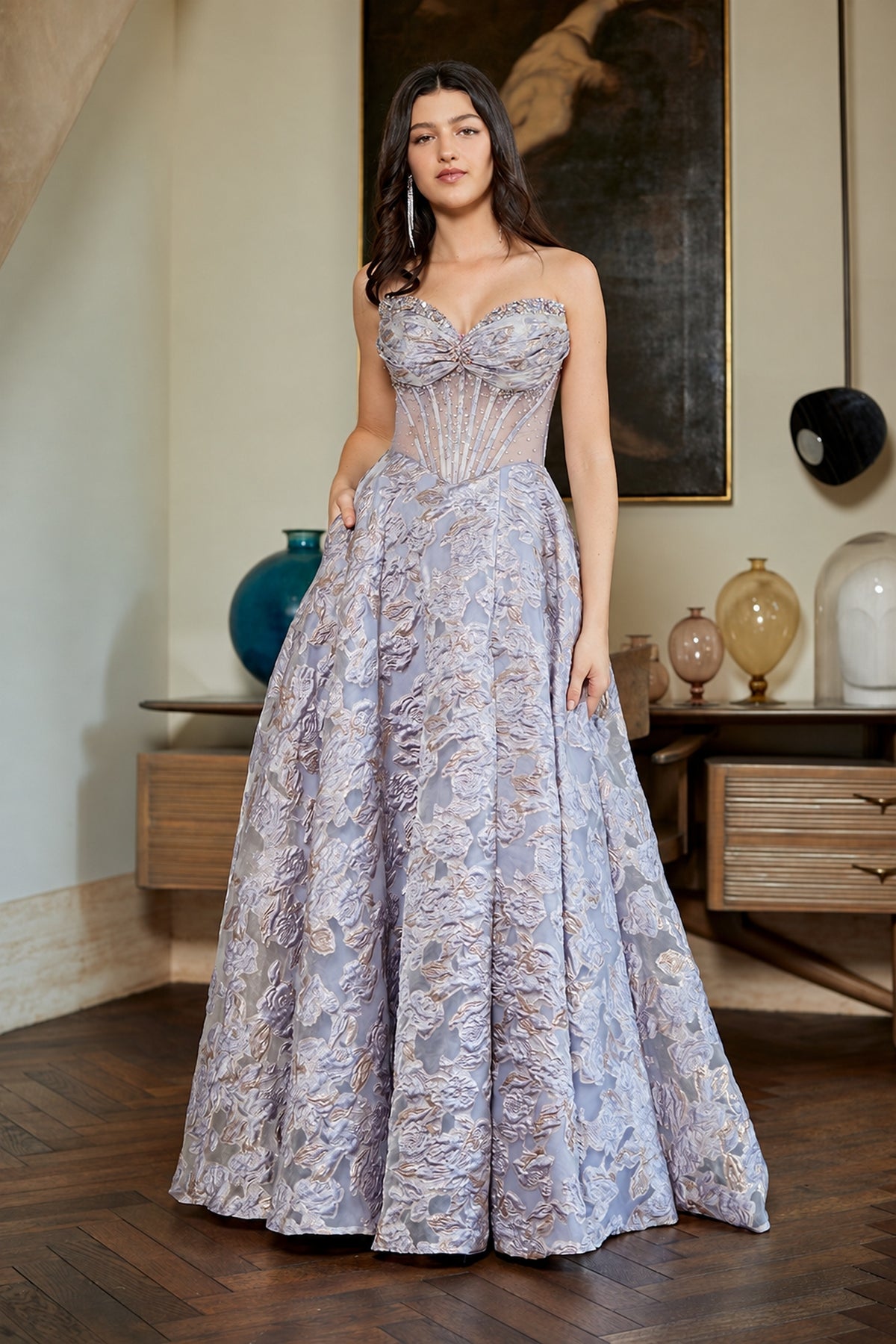 A person wearing the lilac Amelia Couture 8098 prom dress, featuring a strapless, structured corset bodice and a full, textured skirt.