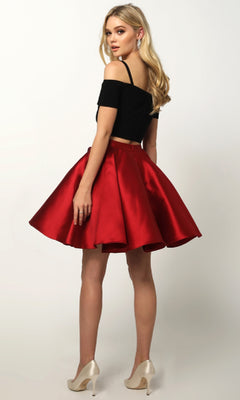 A woman faces away, wearing the Juliet 809 short party dress with off-the-shoulder sleeves, a flared red A-line skirt, and cream heels; her long blonde hair styled loosely.