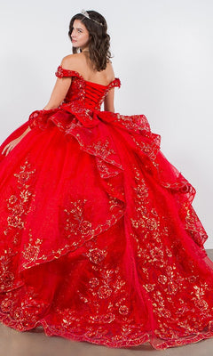 A woman wearing the Quinceanera Ball Gown 8100J, featuring gold floral embroidery, iridescent beading, and an off-the-shoulder design with a tiara, stands facing away from the camera.
