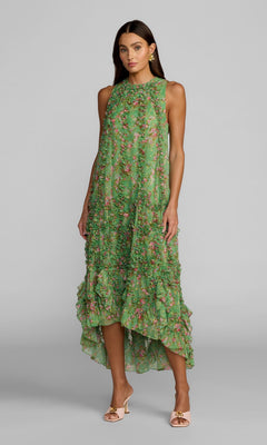 A woman wearing the Mac Duggal 8103 Midi Floral Wedding Guest Dress, a sleeveless green dress with ruffled layers, stands against a plain gray background.