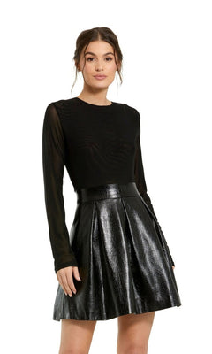 A woman models the Sleeved Short Black Dress 81070 by Mac Duggal, featuring a long-sleeve black mesh top and a high-waisted, pleated shiny skirt, standing against a plain white background.