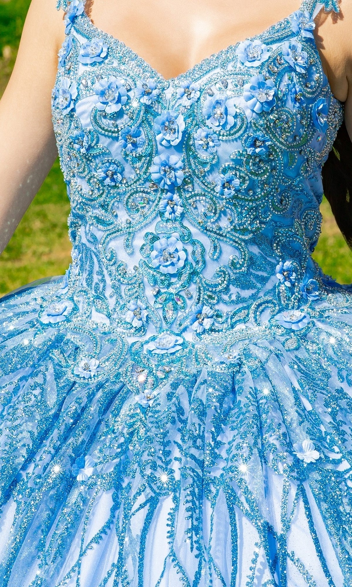 A close-up of the Quinceanera Ball Gown 8110J highlights its intricate beading, embroidered bodice, and delicate floral details, all displayed outdoors.