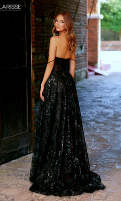 A woman in the Clarisse Designs 811190 Long Prom Dress—featuring a strapless black sequin gown with a corset bodice—stands on a stone pathway, glancing over her shoulder at the camera.